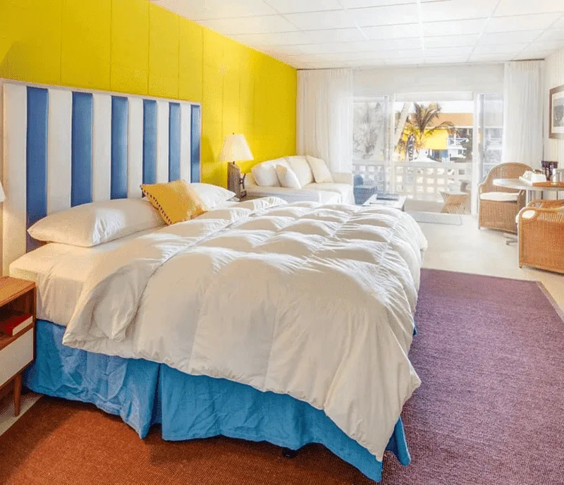 A bright deluxe guest room at Bimini Big Game Club with a blue-and-yellow color scheme and a private balcony