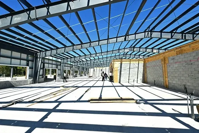 Steel-framed interior of South Bimini Airport's new international terminal under construction, with officials touring the site