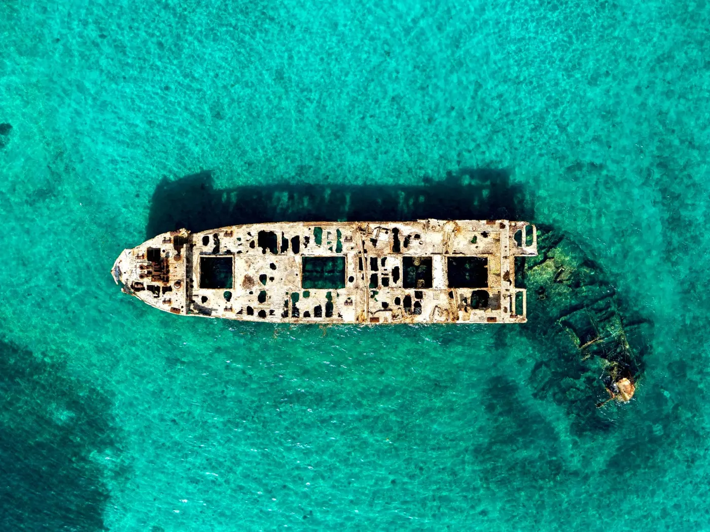 Aerial view of the rusted, concrete-hulled SS Sapona shipwreck resting in shallow turquoise water off South Bimini